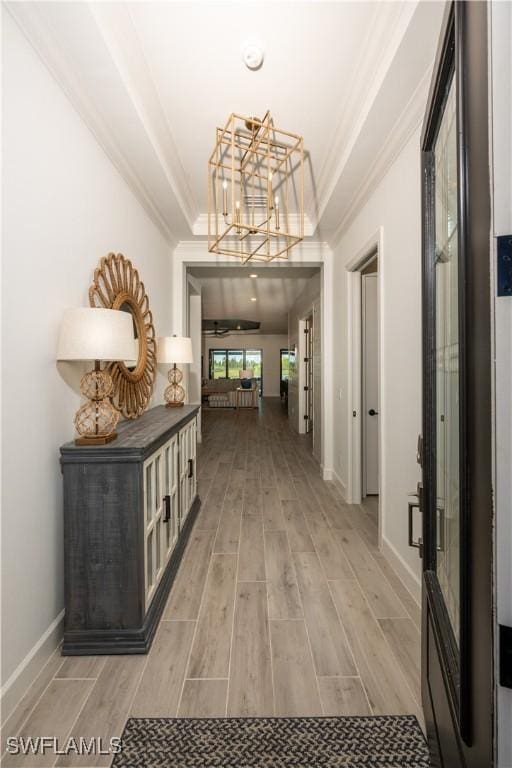 17554 Terracina Dr, Fort Myers, FL 33913 - hall with crown molding, an inviting chandelier, a raised ceiling, light wood finished floors, and baseboards