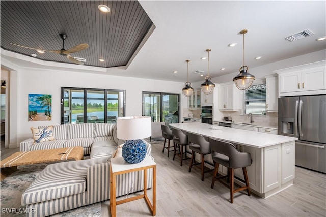 17554 Terracina Dr, Fort Myers, FL 33913 - kitchen with white cabinets, visible vents, light countertops, stainless steel fridge, and a spacious island