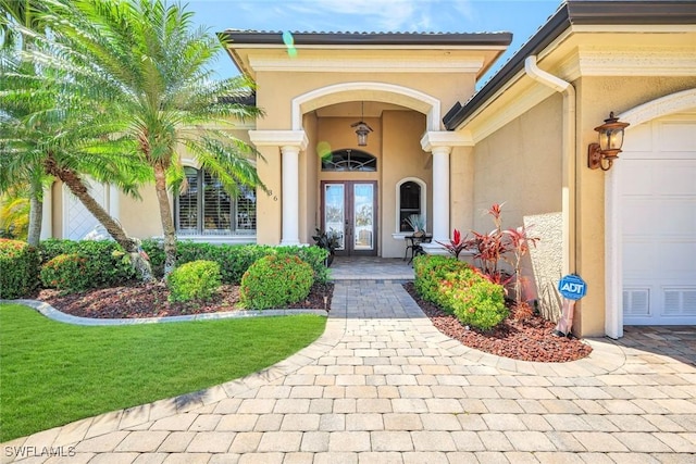 4536 SW 12th Pl, Cape Coral, FL 33914 - view of exterior entry with french doors, an attached garage, and stucco siding