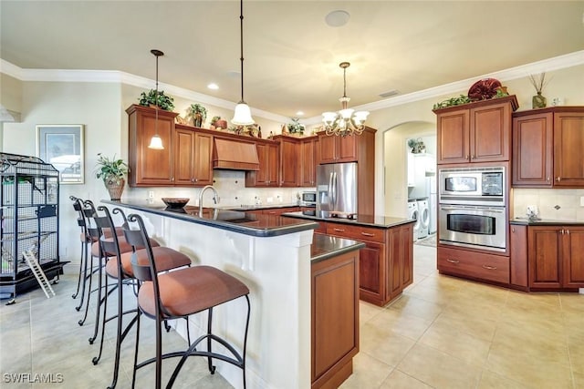 4536 SW 12th Pl, Cape Coral, FL 33914 - kitchen with custom range hood, backsplash, dark countertops, washer / dryer, and appliances with stainless steel finishes