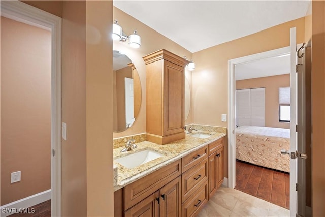 full bath featuring wood finished floors, double vanity, a sink, and connected bathroom