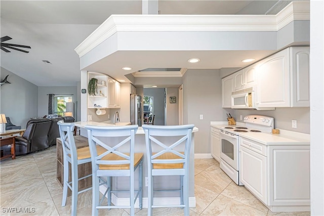 1633 Barbarosa Ct, Marco Island, FL 34145 - kitchen with white appliances, a peninsula, white cabinetry, light countertops, and a breakfast bar area