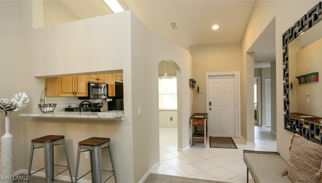 6645 Huntington Lakes Cir Unit 201, Naples, FL 34119 - foyer entrance featuring arched walkways, visible vents, baseboards, and light tile patterned floors