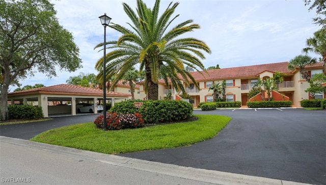 6645 Huntington Lakes Cir Unit 201, Naples, FL 34119 - view of front facade featuring stucco siding, covered parking, and a tiled roof