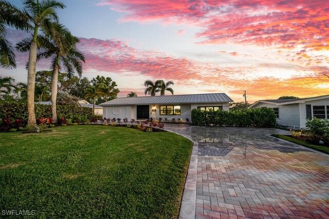148 1st St, Bonita Springs, FL 34134 - view of front of home featuring a lawn, a standing seam roof, metal roof, and decorative driveway