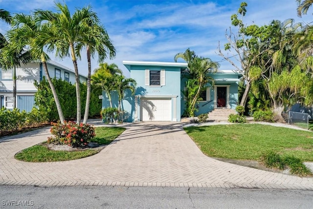 tri-level home featuring a garage, stucco siding, decorative driveway, and a front lawn