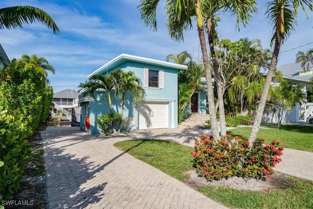 view of front of home with stucco siding, decorative driveway, an attached garage, and a front lawn