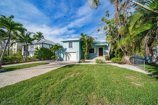 view of front of property featuring stucco siding, a front yard, fence, an attached garage, and driveway