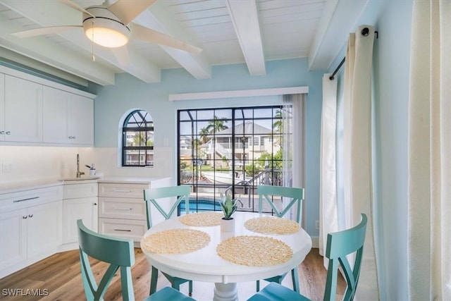 dining space with beam ceiling, ceiling fan, and light wood-type flooring