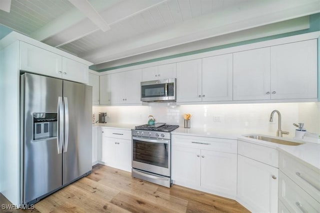 kitchen with white cabinetry, backsplash, beam ceiling, stainless steel appliances, and a sink
