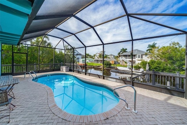 outdoor pool with a lanai, a patio area, and a water view