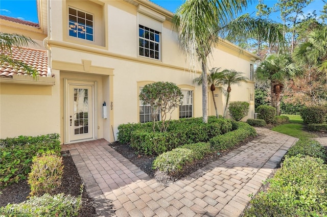 doorway to property with a tiled roof and stucco siding
