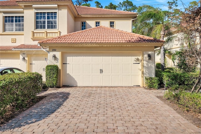 mediterranean / spanish-style home featuring a tiled roof, decorative driveway, and stucco siding