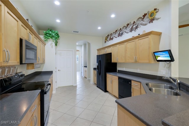 kitchen featuring light brown cabinetry, a sink, black appliances, and dark countertops