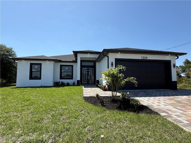 prairie-style house featuring a garage, a front yard, driveway, and stucco siding