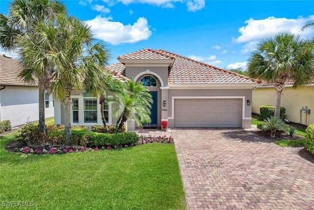 9102 Limestone Ln, Naples, FL 34120 - mediterranean / spanish home featuring a tiled roof, an attached garage, decorative driveway, and stucco siding