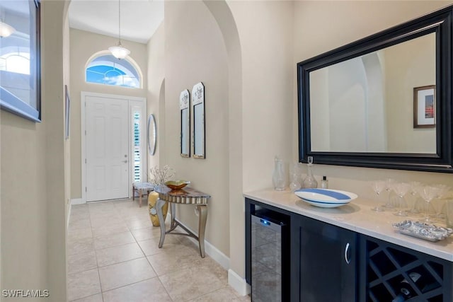 9102 Limestone Ln, Naples, FL 34120 - entryway with arched walkways, bar area, light tile patterned flooring, beverage cooler, and baseboards
