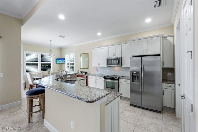 9102 Limestone Ln, Naples, FL 34120 - kitchen featuring an island with sink, visible vents, a sink, stainless steel appliances, and backsplash
