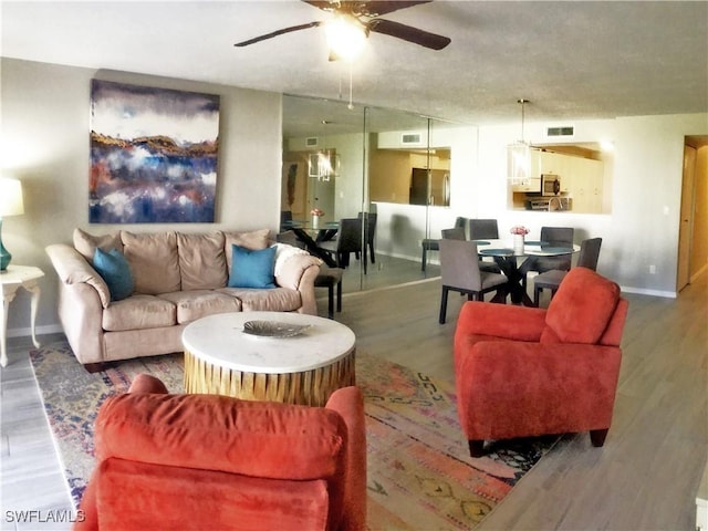 living room with ceiling fan, baseboards, wood finished floors, and visible vents