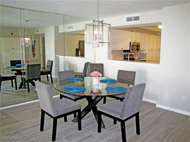 dining room featuring a chandelier, light wood-style floors, visible vents, and baseboards