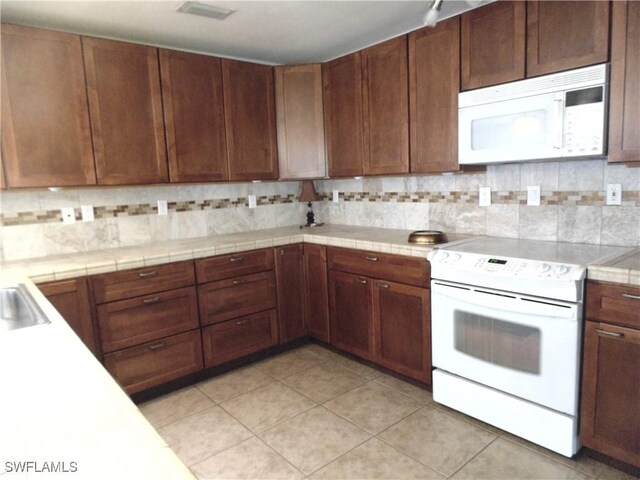 18215 Iris Rd, Fort Myers, FL 33967 - kitchen featuring visible vents, light tile patterned floors, light countertops, white appliances, and decorative backsplash