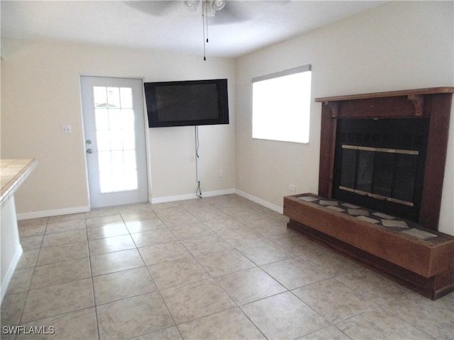 18215 Iris Rd, Fort Myers, FL 33967 - unfurnished living room featuring a glass covered fireplace, baseboards, light tile patterned flooring, and ceiling fan