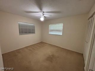 18215 Iris Rd, Fort Myers, FL 33967 - unfurnished bedroom with carpet floors, a closet, and a ceiling fan