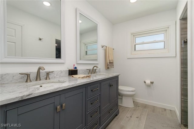 bathroom with toilet, wood finished floors, a sink, and baseboards