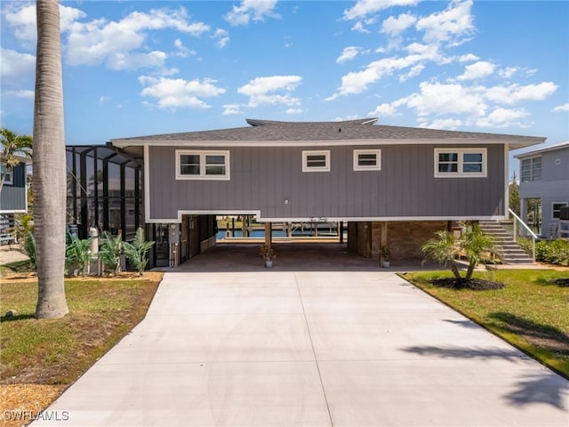 view of front of house with stairway, driveway, a carport, and a shingled roof