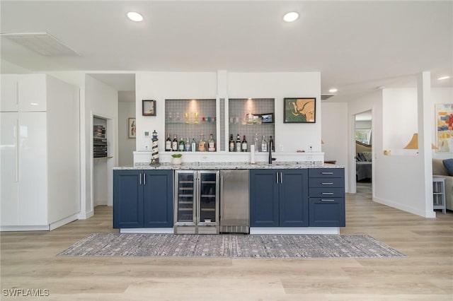 bar with freestanding refrigerator, light wood-style floors, wet bar, and wine cooler
