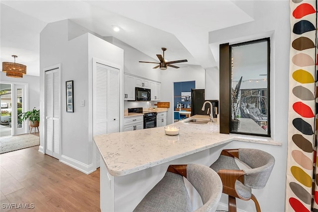 171 Palmetto Dunes Cir, Naples, FL 34113 - kitchen with black appliances, a sink, a peninsula, white cabinetry, and a breakfast bar area