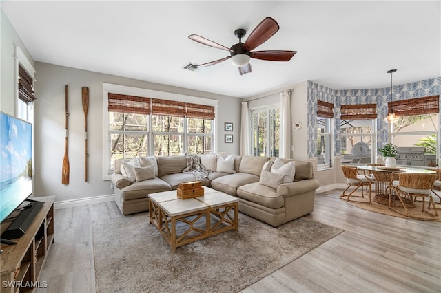living area featuring ceiling fan, a wealth of natural light, wood finished floors, and visible vents