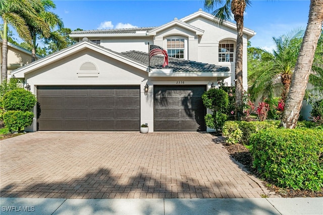 view of front facade with an attached garage, decorative driveway, and stucco siding