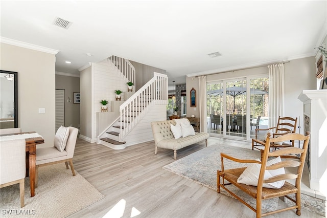 living area with visible vents, crown molding, wood finished floors, baseboards, and stairs