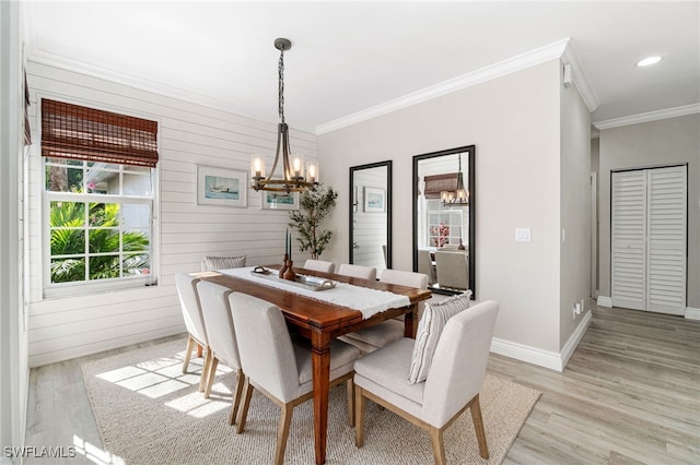dining space with light wood-style floors, baseboards, ornamental molding, and a notable chandelier