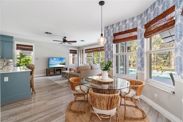 dining area with baseboards, wallpapered walls, a ceiling fan, and light wood finished floors