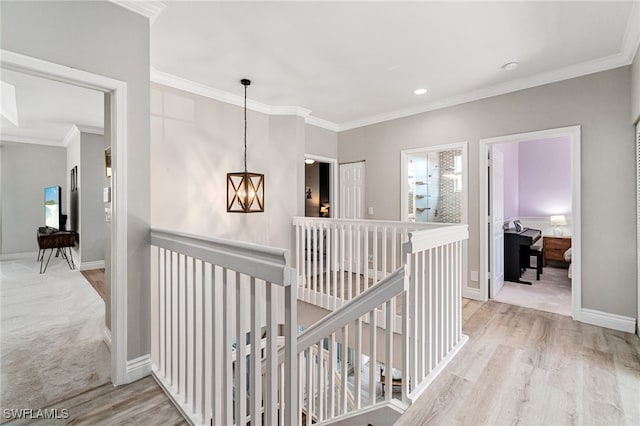 corridor with an upstairs landing, ornamental molding, and light wood-style floors