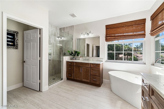 bathroom with vanity, a freestanding tub, a healthy amount of sunlight, and a stall shower
