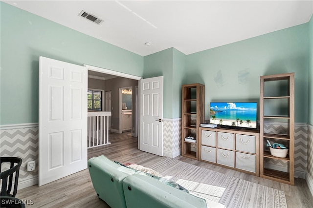 living area with baseboards, visible vents, wainscoting, and wood finished floors