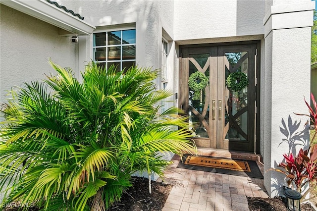 property entrance with stucco siding and french doors