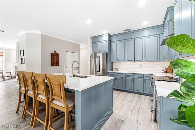 kitchen with backsplash, visible vents, appliances with stainless steel finishes, a sink, and light countertops