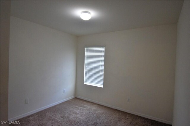 spare room featuring light carpet and baseboards