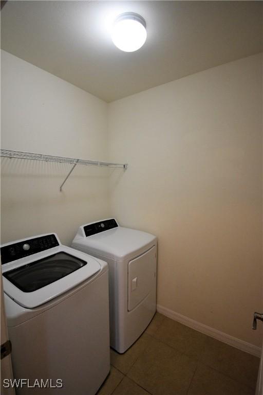 laundry area featuring laundry area, light tile patterned floors, baseboards, and washer and clothes dryer
