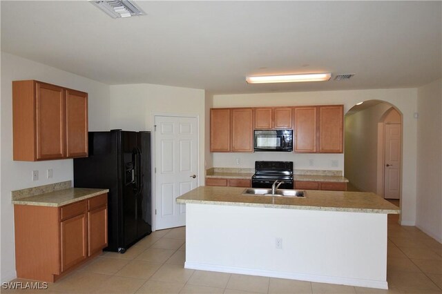 kitchen with brown cabinetry, visible vents, a sink, and black appliances