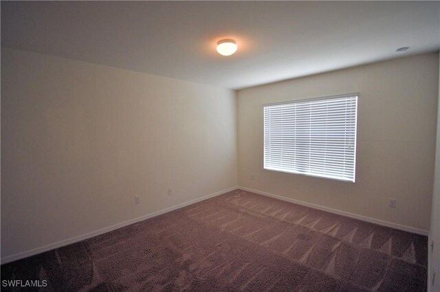 carpeted empty room featuring baseboards