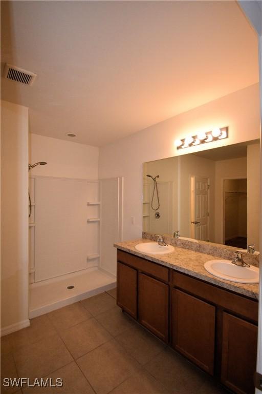 full bathroom featuring a sink, visible vents, a walk in shower, and tile patterned flooring