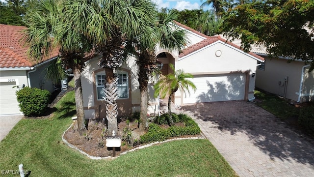 view of front of property with stucco siding, decorative driveway, a front lawn, an attached garage, and a tile roof