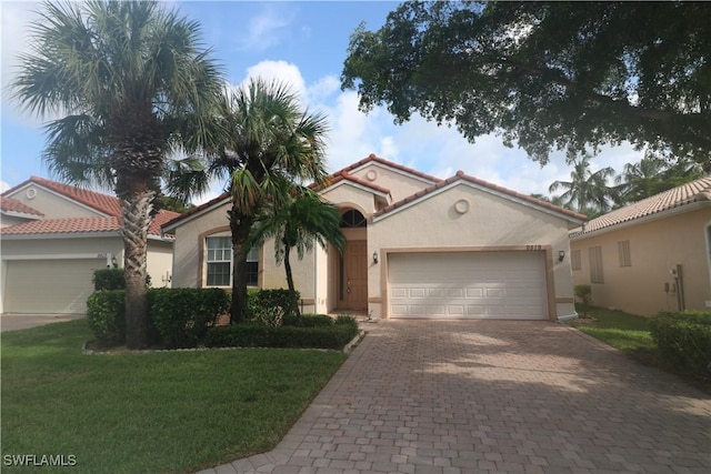 mediterranean / spanish house featuring a front yard, stucco siding, decorative driveway, and an attached garage