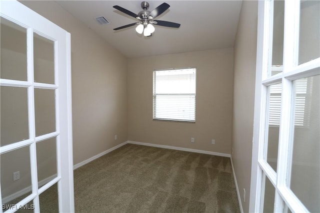 carpeted empty room with baseboards, a ceiling fan, and visible vents