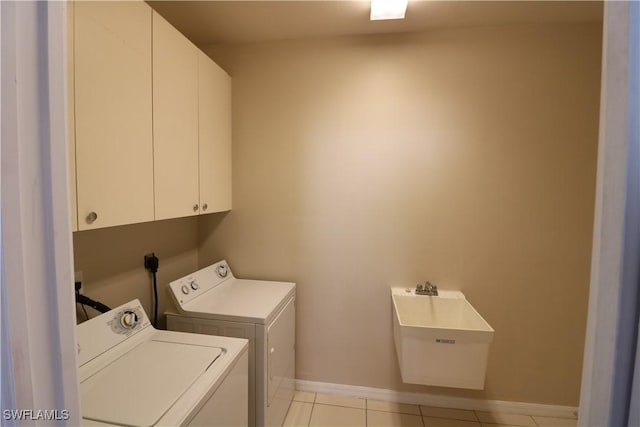 laundry room featuring light tile patterned floors, baseboards, washer and dryer, a sink, and cabinet space